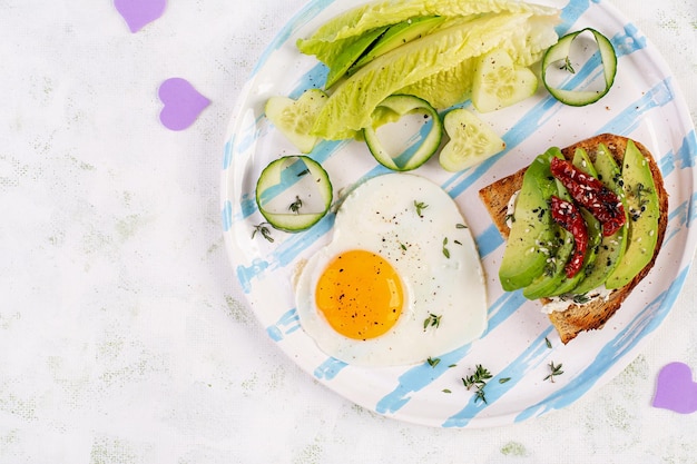 Romantic breakfast for Valentines Day Fried egg and toast with avocado and cream cheese Top view