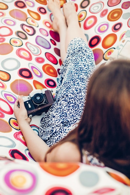 Photo romantic brunette girl in beautiful dress lying on a hammock with film camera hat and book hipster leisure on summer vacation concept