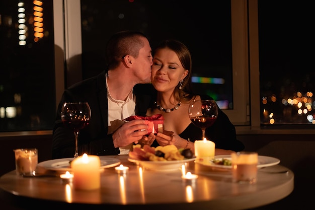 Foto cena romantica a lume di candela per due appuntamento di san valentino coppia autentica a cena un uomo che dà un regalo a una donna relazione familiare romantica