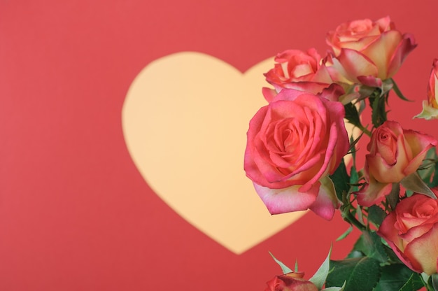 Romantic card with yellow heart and roses on a red surface