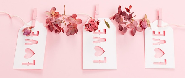 Romantic cards with the inscription Love, dry roses and hydrangea flowers on pink background. Flat lay, top view