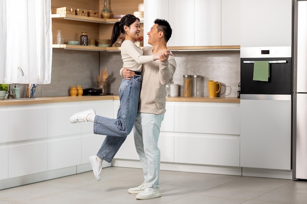 Romantic chinese lovers dancing waltz at kitchen