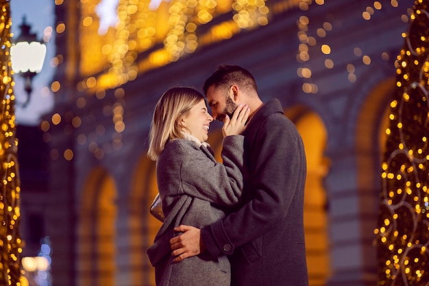 Romantic Christmas lovers laughing and hugging on the street on New Year's eve