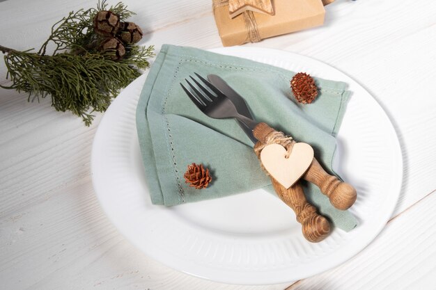 romantic christmas table setting with eco-friendly linen napkin and wooden heart decoration