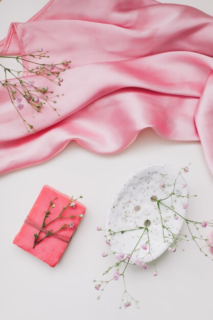 Romantic composition with a pink soap with ceramic dish and silver dress