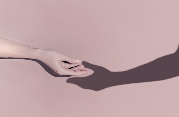 Romantic concept. A woman's hand reaches out towards the shadow of a man's hand which pulls towards