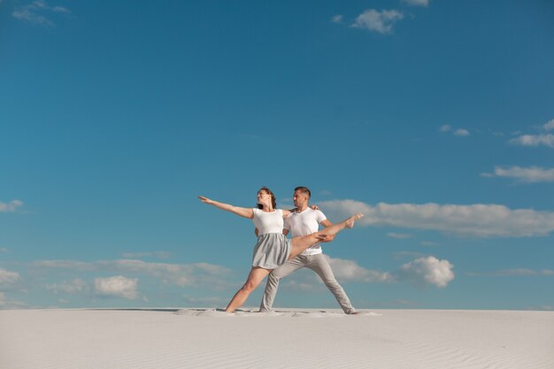 Romantic couple dancing in sand desert at blue sky background.