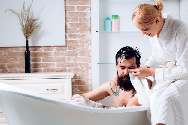 Romantic couple enjoying sensual couple of woman and man trimming with razor couple in bath grooming...