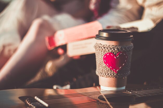 Романтическая пара, пикник в свете заката Кофейная чашка уютный вязаный рукав с фетровым красным сердцем