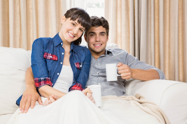 Romantic couple at home relaxing on the sofa having coffee