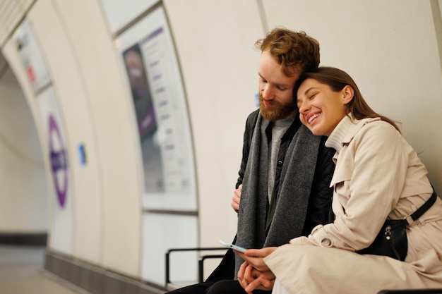 Романтическая пара сидит в объятиях на скамейке станции метро