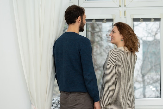 Romantic couple looking out of the window. Quarantine at home.