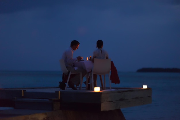 romantic couple  in love have dinner in outdoor restaurant with candles with sea in background