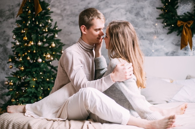 Романтическая пара отдыхает на кровати у себя дома на Рождество