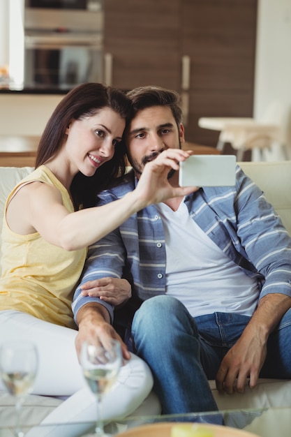 Coppie romantiche che si rilassano sul sofà e che prendono un selfie