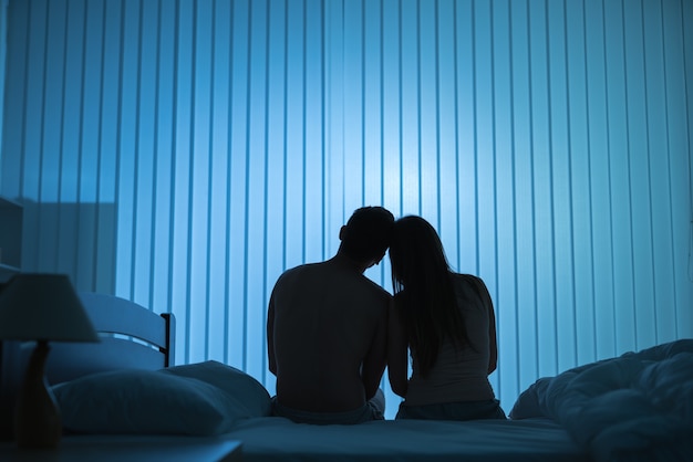 The romantic couple sit on the bed. night time