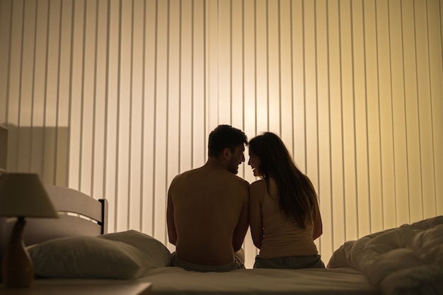 The romantic couple sit on the bed