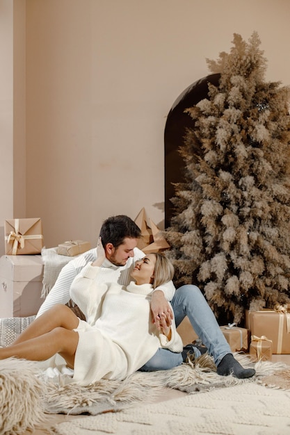 Romantic couple sitting on a floor near Christmas tree at home