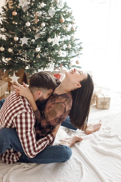 Romantic couple sitting near Christmas tree and hugging