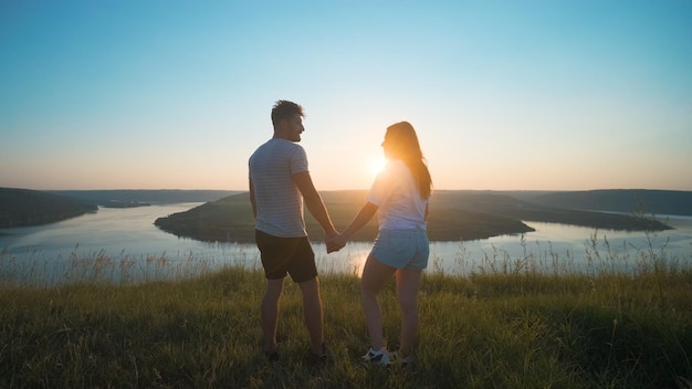 The romantic couple standing on a mountain top on a beautiful river background