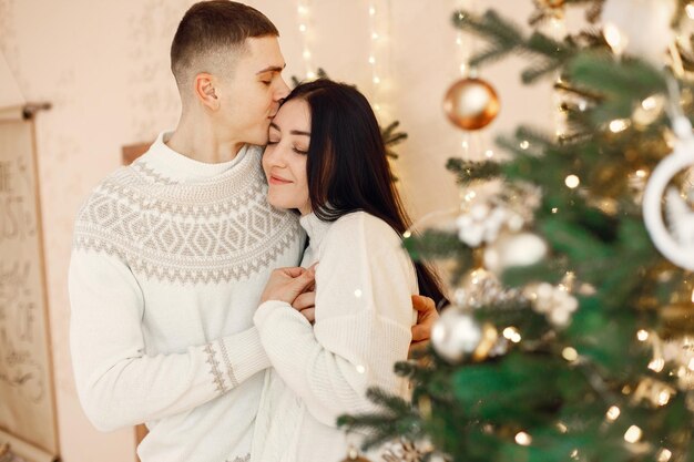romantic couple standing near christmas tree and hugging