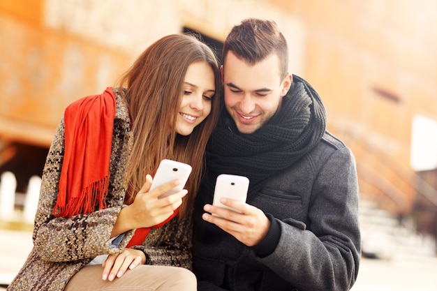 a romantic couple using smart phones during an autumn walk