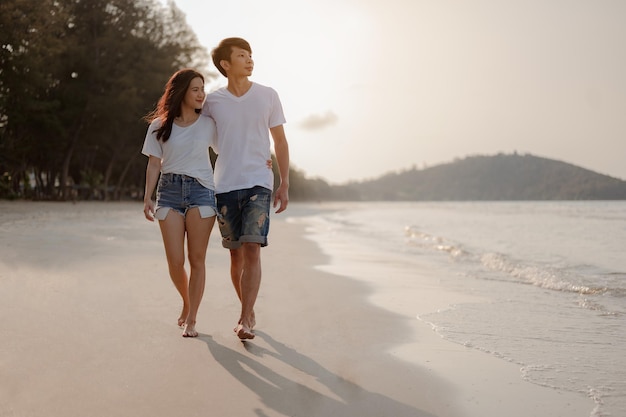 Romantic couple walking holding hands each other while at beach at sunrise, plan life insurance at future concept. copy space for text. couple, love, beach, romantic, summer, lifestyle concept.