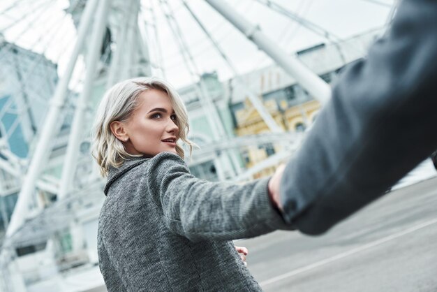 Romantic date outdoors young couple walking at entertainment park holding hands woman closeup