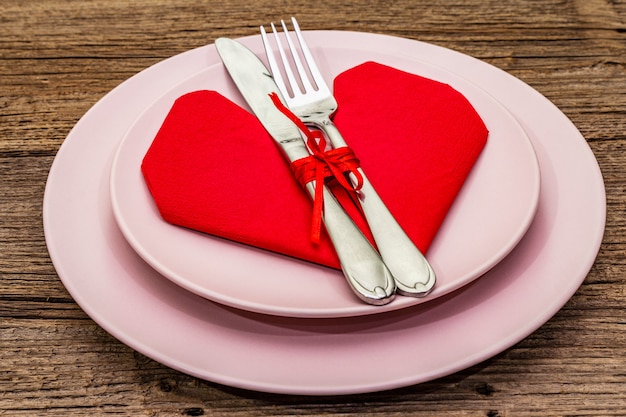 Romantic dinner table with plates and heart shape napkin