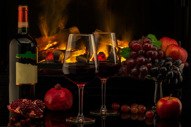 Romantic dinner with wine and grapes on the background of the fireplace.