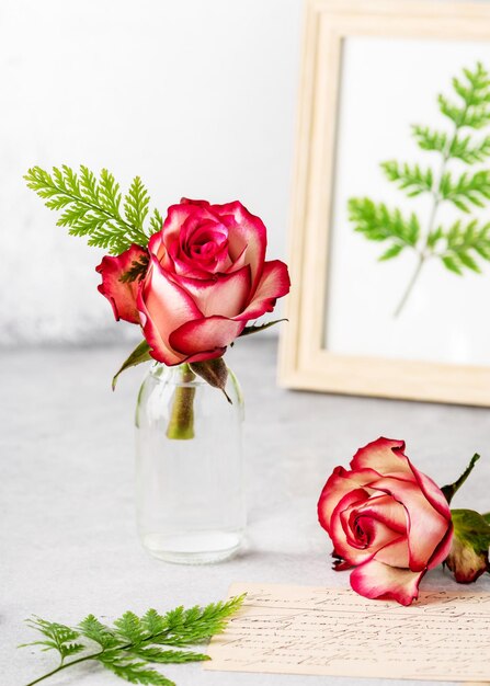 Romantic flower arrangement with red roses and green fern leaves in glass vase