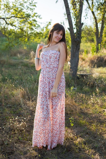 Romantic girl in long floral dress walk in summer garden