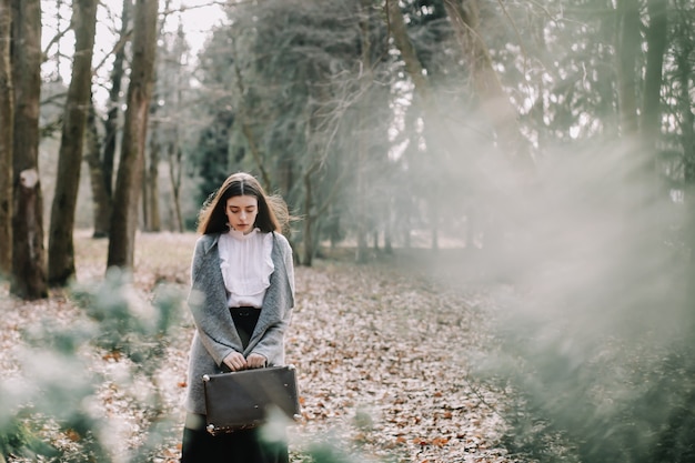 romantic girl with a vintage suitcase in the park adventure vacations travel concept