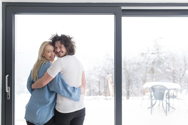 추운 겨울날 집에서 창가에서 모닝 커피를 즐기는 낭만적인 행복한 젊은 커플