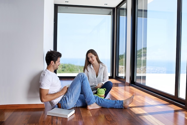 ロマンチックな幸せな若いカップルは屋内の現代家の階段でリラックスします。