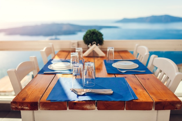 Foto il tavolo da pranzo romantico della luna di miele è servito sull'isola di santorini, in grecia con il paesaggio delle montagne e della spiaggia, vista del vulcano.