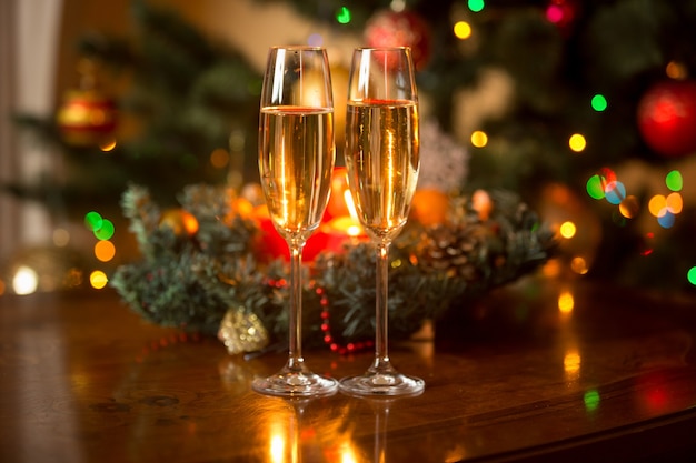 Romantic image of two glasses of champagne and Christmas wreath with candles on wooden table