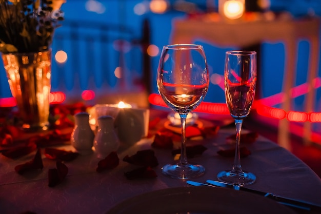 romantic luxury evening with champagne setting with two glasses rose petails and candles