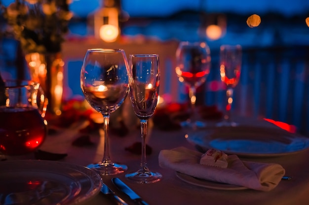 Foto serata romantica di lusso con champagne con due bicchieri di petali di rosa e candele