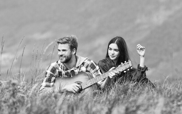 Romantic mood Couple in love enjoying view from top of mountain Boyfriend playing guitar Singing for her Romantic hike Romantic couple on summer vacation Idyllic place for romantic date