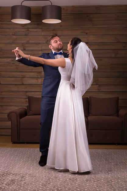 Romantic newlyweds couple dancing wedding dance on wooden room