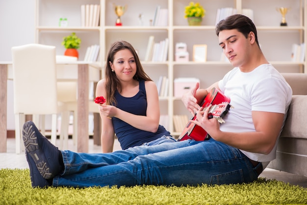 Photo romantic pair playing guitar on floor