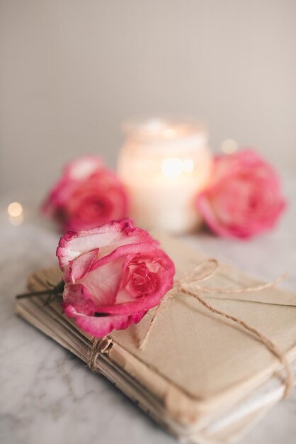 테이블에 장미 꽃으로 묶인 낭만적인 종이 접힌 편지는 달팽이 메일과 오래된 추억 위에 닫혀 있습니다.