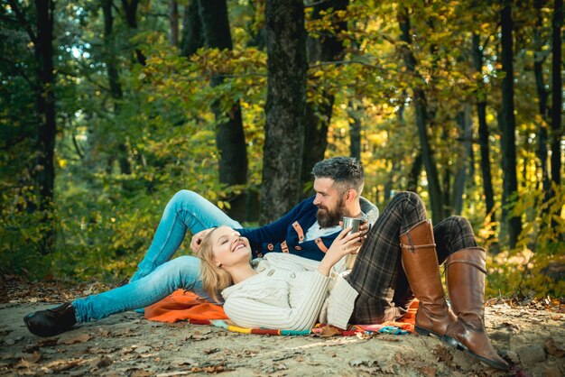ロマンチックなピクニックの森。ピクニック毛布でリラックスした愛の観光客のカップル。自然の中でロマンチックなデート。私たち二人だけが周りの自然です。観光の概念。ピクニックタイム。一緒に公園でリラックスするカップル