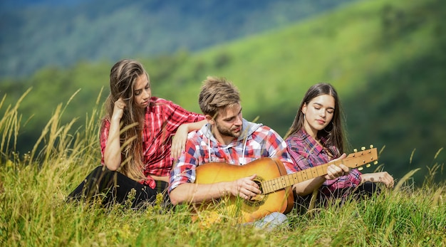 Romantic picnic in tourism camp. campfire songs. group of people spend free time together. family camping. hiking adventure. happy men and girls friends with guitar. friendship. Feeling comfortable.