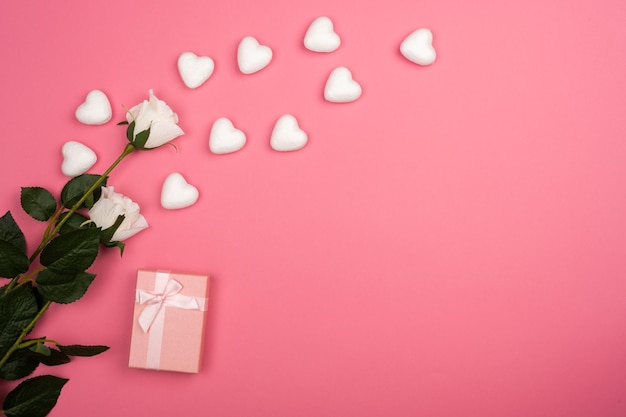 romantic pink background with white roses small white heats and pink gift box