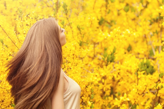 Foto ritratto romantico di bella donna con lunghi capelli che soffia su sfondo floreale