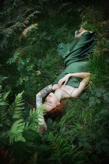 Romantic portrait of a woman in a fern in the forest. Art woman natural makeup resting in nature. Green fern thickets