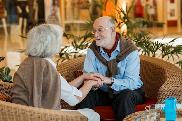 Romantic senior couple holding hands in cafe