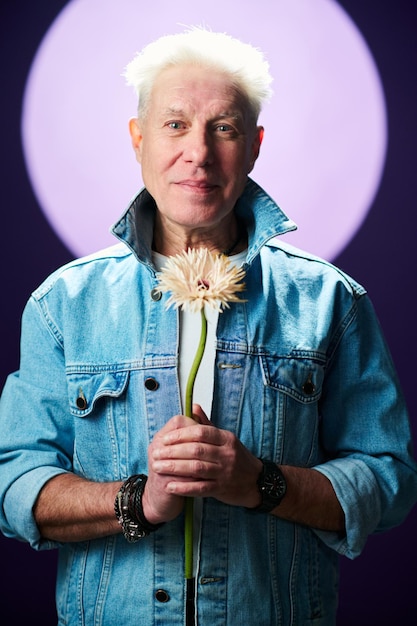 Romantic senior man with flower standing against full moon at night